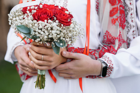 Romantic Embrace with a Red Rose Bouquet in Traditional Attire.の写真素材