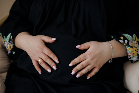 Expectant Mother Cradling Baby Bump in Elegant Black Dress.の写真素材