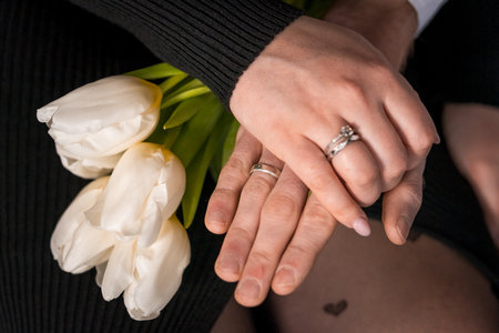 Romantic Gesture of Commitment with White Tulips and Intertwined Hands.の写真素材
