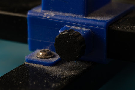 Close-up of a Blue Adjustment Knob on a Black Device with Dust Particles.の写真素材