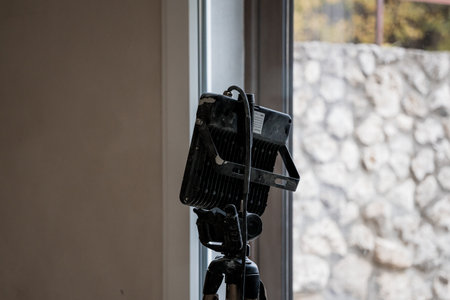 Spotlight on a Tripod Next to a Window in a Stone Wall Setting.の写真素材