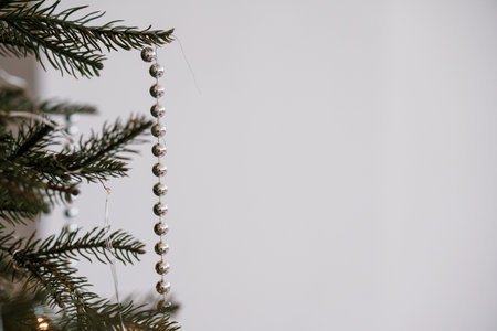 Elegant Silver Beads Hanging from a Christmas Tree Branch.の写真素材