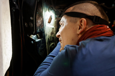 Mechanic Inspecting Engine Compartment with Headlamp.