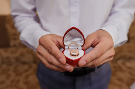 Elegant Wedding Rings in Red Velvet Box Held by a Groom.の写真素材
