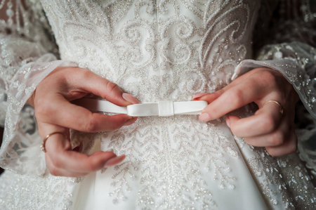 Elegant Bride Adjusting Her Embellished Wedding Dress with Delicate Hands.の写真素材