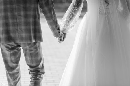 A Romantic Black and White Photograph of a Bride and Groom Holding Hands Together.の写真素材