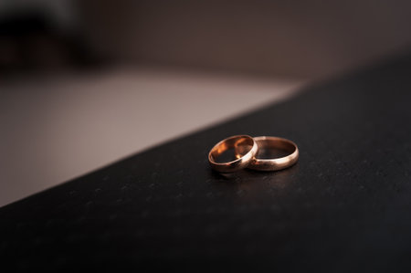 Elegant close-up of intertwined wedding rings on a textured surface.の写真素材