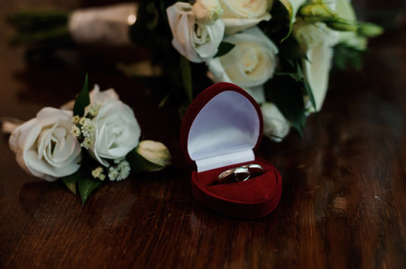 Elegant Wedding Rings Displayed with Beautiful Bouquet on a Wooden Table.