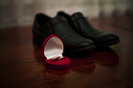 Elegant Wedding Rings on a Polished Surface Near Black Formal Shoes.