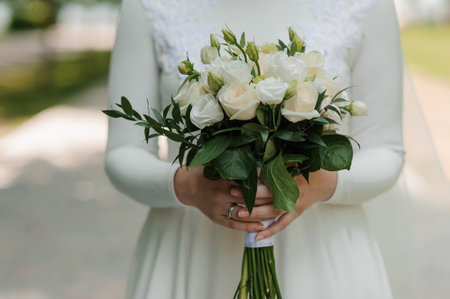 Elegant Bride Holding a Lush Floral Bouquet in a Garden Setting.の写真素材