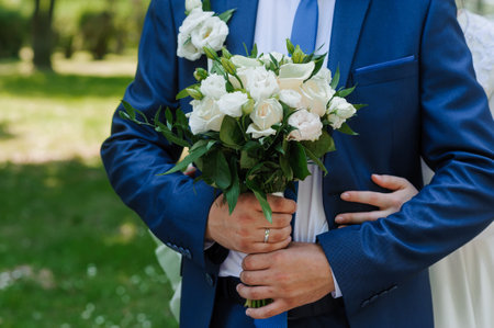 Romantic Wedding Couple Holding White Rose Bouquet in Lush Greenery.の写真素材
