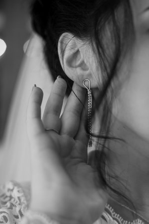 A Close-Up of a Bride Adjusting Her Modern Earring in Black and White.の写真素材
