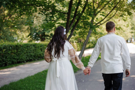Romantic Couple Walking Hand in Hand in a Lush Green Park on Their Wedding Day.の写真素材