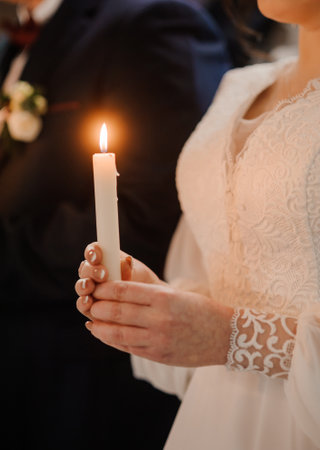 A Bride Holding a Lit Candle During a Romantic Wedding Ceremony.の写真素材