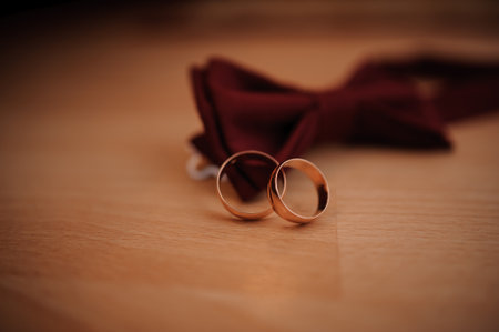 Elegant Wedding Rings and Bowtie on Wooden Surface.の写真素材