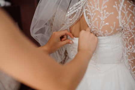 Bridal Preparation Moments: A Close-Up of a Woman in a Wedding Dress Being Fastened.の写真素材