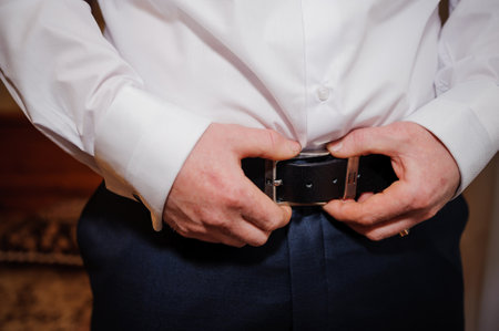 Groom Adjusting Belt Before Wedding Ceremony.