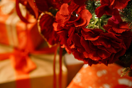 Festive Red Carnations Surrounded by Holiday Gifts and Ornaments.の写真素材