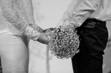 Romantic Black and White Wedding Moment with Hands Holding a Baby's Breath Bouquet.の写真素材