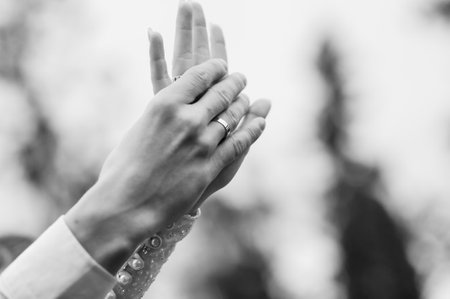 Union of Love: A Close-Up of Intertwined Hands Showcasing Wedding Rings in Black and White.の写真素材