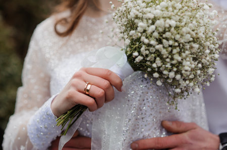 Elegantly Adorned Bride Holding Baby's Breath Bouquet in Romantic Wedding Setting.の写真素材