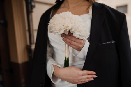 Elegant Bride Holding White Carnations in Stylish Attire.の写真素材