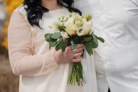 Elegant Bride Holding a White Floral Bouquet in a Romantic Outdoor Setting.の写真素材