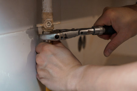 A Close-Up of a Hand Using a Wrench to Adjust a Plumbing Valve.