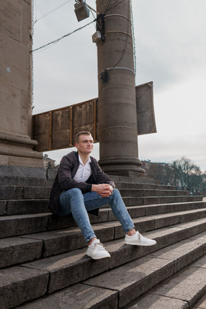 Urban Portrait of a Young Man Relaxing on Stone Steps