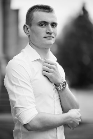 Portrait of a Young Man in a White Shirt with a Watch Outdoors.の写真素材