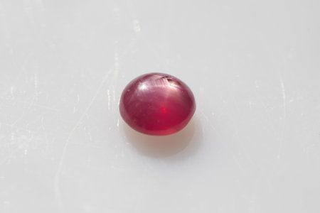 Natural 6 Star Red Ruby Gemstone Polished Cabochon on Glossy White Surface.の写真素材