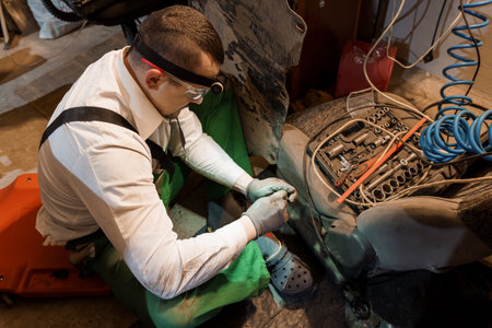 Professional Mechanic in Safety Gear Repairing Vehicle Parts in Workshop.