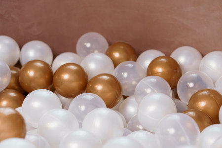 Close-Up of White, Golden and Transparent Plastic Balls in a Ball Pit Playground Area.の写真素材