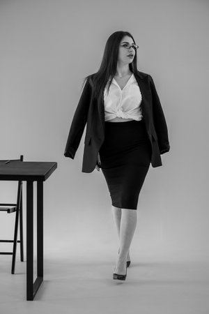 Confident businesswoman walking in modern office space, professional attire, black and white portraitの写真素材