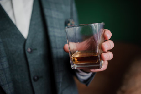 A well-dressed man, likely in his thirties, dressed in a textured gray plaid suit and white shirt,...