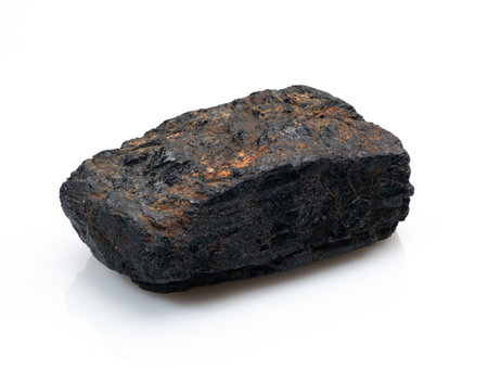 A close-up shot features a rough, uncut black tourmaline mineral specimen, showing its dark, earthy texture and natural crystalline formation, ideal for healingの写真素材