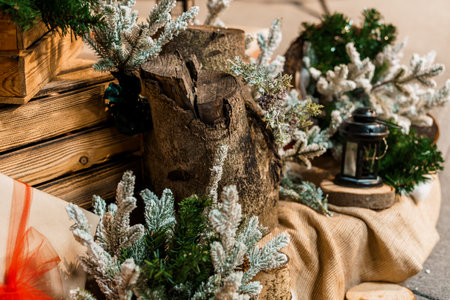 A charming still life scene wooden features logs adorned with frosted pine branches, a vintage lantern, and burlap fabric creating a cozy, festive mood for Christmasの写真素材