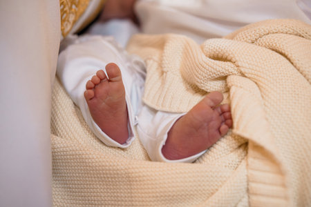 Close-up view of a newborn babys small feet covered with a soft, cream-colored knitted blanket...