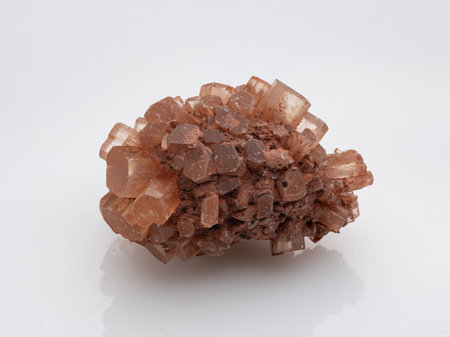This image features an attractive cluster of natural orange-brown aragonite crystals with a rough, geode-like texture, presented on a white backdropの写真素材