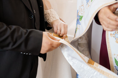 A close-up of an Orthodox Jewish wedding exchange of rings with the rabbi's tallit covering the hands, symbolizing commitment and blessing, realistic styleの写真素材