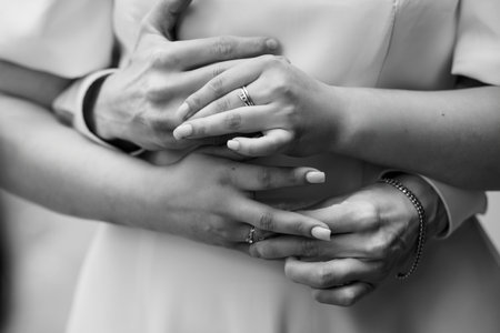 Romantic close-up of a couple's hands clasped together, displaying wedding rings, symbolizing love,...