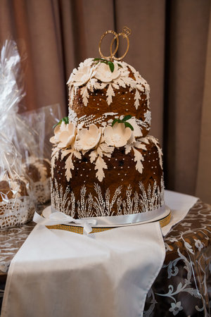 Beautifully decorated two-tiered wedding cake adorned with wheat and white flowers, topped with...