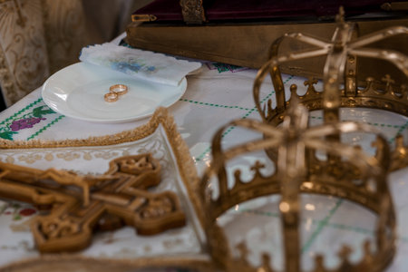 Orthodox Wedding Ceremony Details: Gold Crown, Rings, Crosses, Embroidered Cloth, and Wooden Chest, Symbolic Still Life in Warm Tonesの写真素材