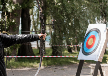 A recurve bow archer aims at a target during outdoor practice. the scene captures sport and...