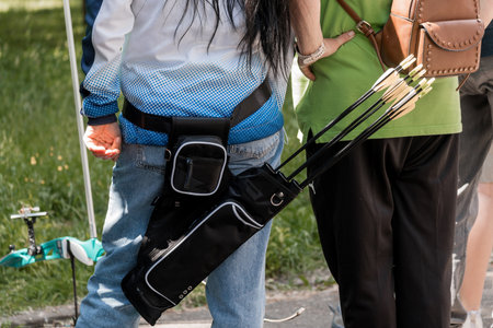 A detailed shot shows an archer's belt with arrows in a green field during outdoor practice,...