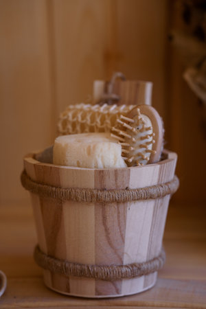 A close-up shot showcases a wooden bucket filled with handmade soap and natural brushes in a minimalist sauna setting, evoking a sense of calm and organic beautyの写真素材