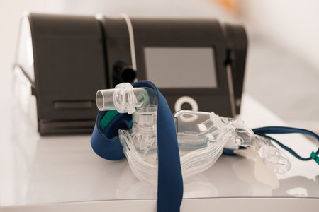 Close-up of a CPAP machine and nasal mask, essential tools for sleep apnea therapy, placed on a clean white surface. focuses on medical device usabilityの写真素材