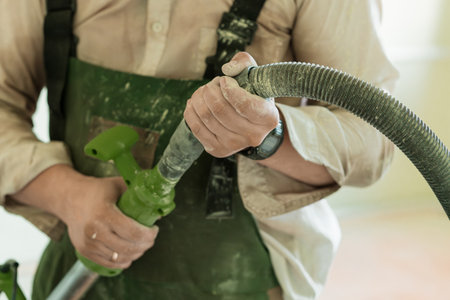 Focused shot of a gardener's hands connecting a green hose, demonstrating landscaping maintenance in...