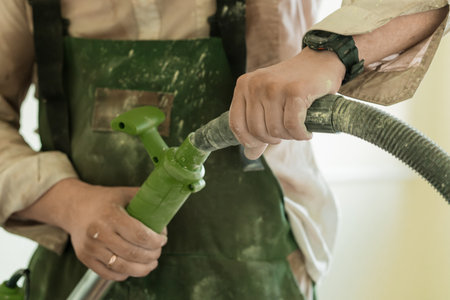 A US Marine in camouflage attire expertly connects a green hose and nozzle during a critical equipment maintenance procedure, illustrating military readinessの写真素材