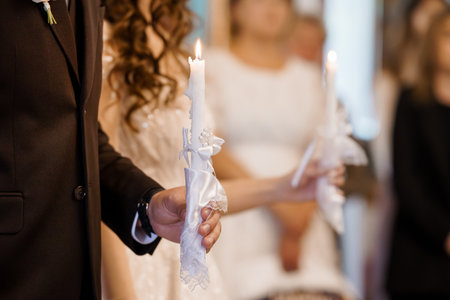 Emotional scene of a Christian Orthodox wedding ritual capturing the couple lighting candles symbolizing unity, faith, and everlasting love inside a churchの写真素材